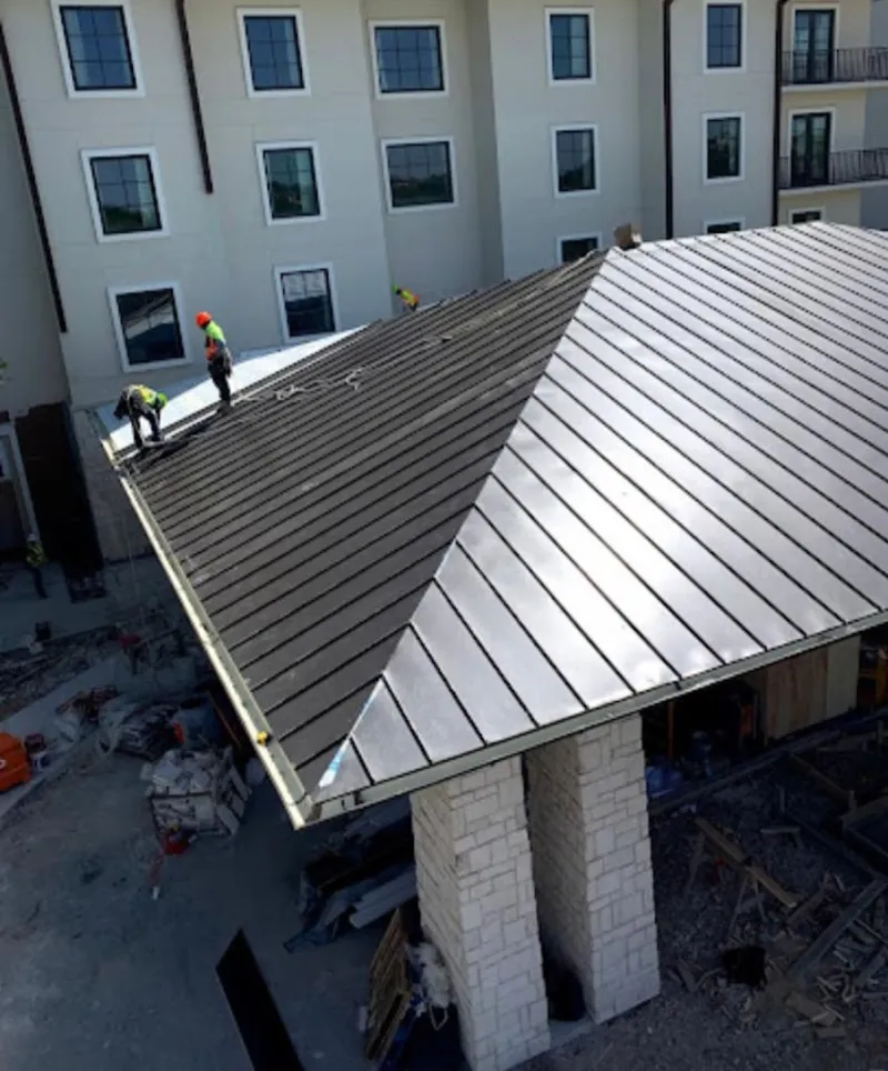 Crew installing standing seam metal roof panels on a commercial project in Amory